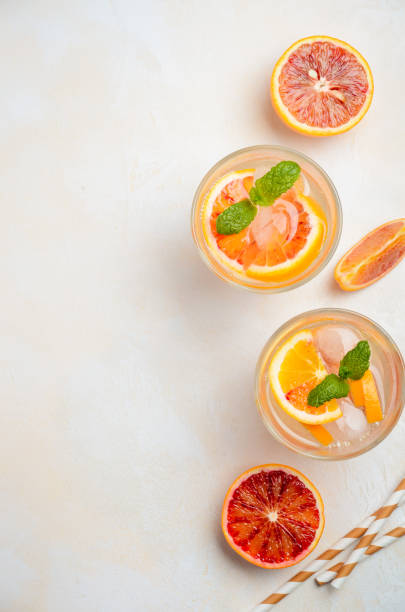 istock Cold refreshing drink with blood orange slices in a glass on a white concrete background. 912262814