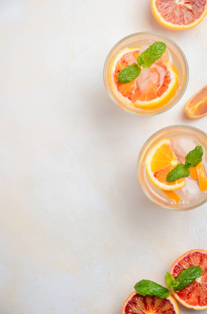 Cold refreshing drink with blood orange slices in a glass on a white concrete background.