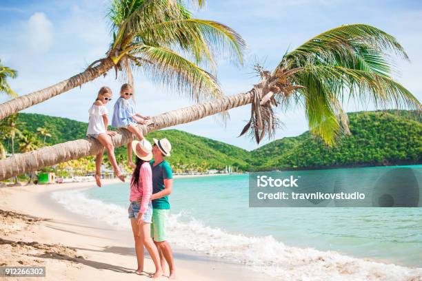 Kids Having Fun Sitting On The Palm Tree Happy Family Relaxing On Tropical Carlisle Bay Beach With White Sand And Turquoise Ocean Water At Antigua Island In Caribbean Stock Photo - Download Image Now