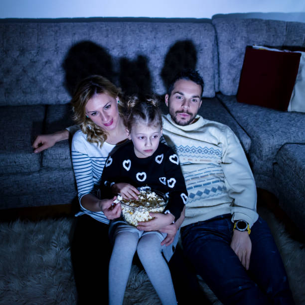 istock Family eating popcorn while watching tv at home 912266414