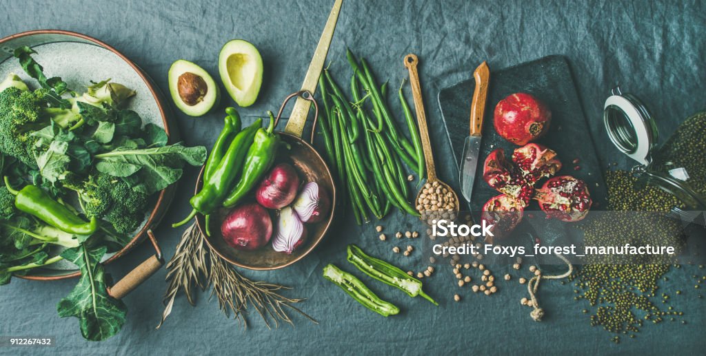 Winter vegetarian or vegan food cooking ingredients, grey linen background Winter vegetarian, vegan food cooking ingredients. Flat-lay of seasonal vegetables, fruit, beans, cereals, kitchen utencils, dried flowers, olive oil over grey linen table cloth background, top view Above Stock Photo