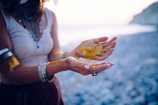 Close-up of hippie woman's hands with silver jewelry and golden glitter at beach festival