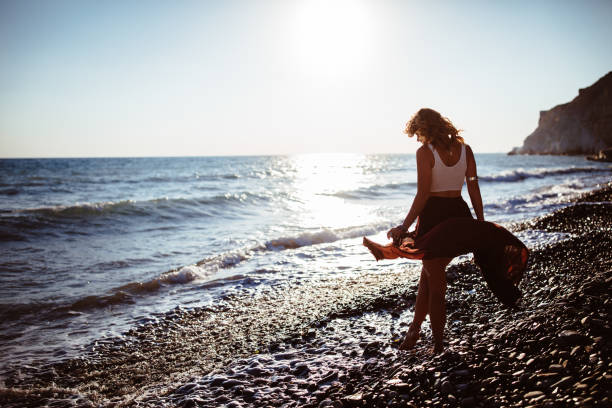 Woman in boho style walking on the beach in summer