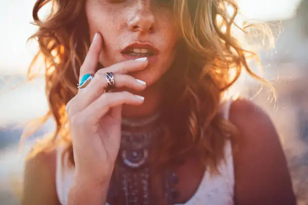 Close-up of bohemian woman with freckles wearing boho style silver turquoise rings and necklaces