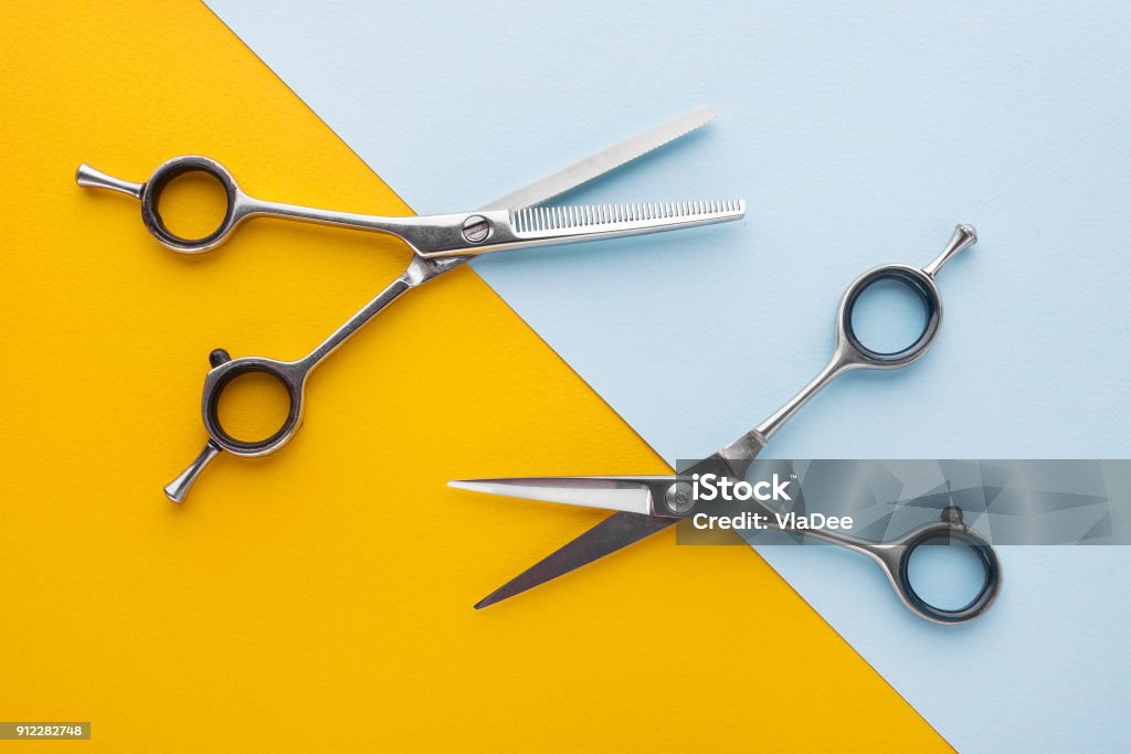 Two sets of stainless steel hairdressing scissors arranged horizontally and parallel to one another Scissors Stock Photo