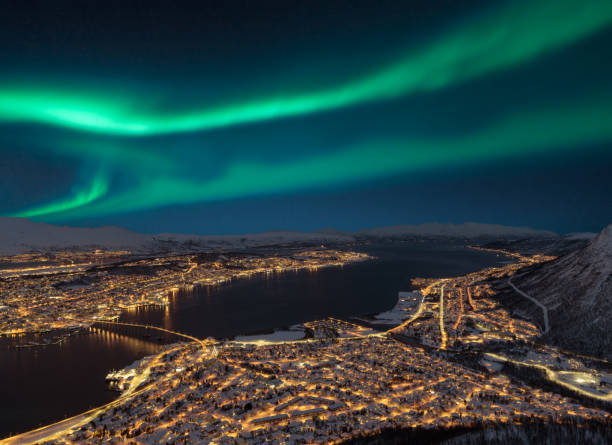 Aerial view at night from Storsteinen hill on Tromso city with beautiful shapes of aurora borealis stock photo