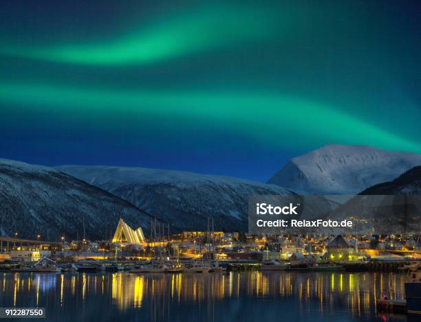 View At Night On Illuminated Tromso City With Cathedral And Majestic Aurora Borealis Stock Photo - Download Image Now