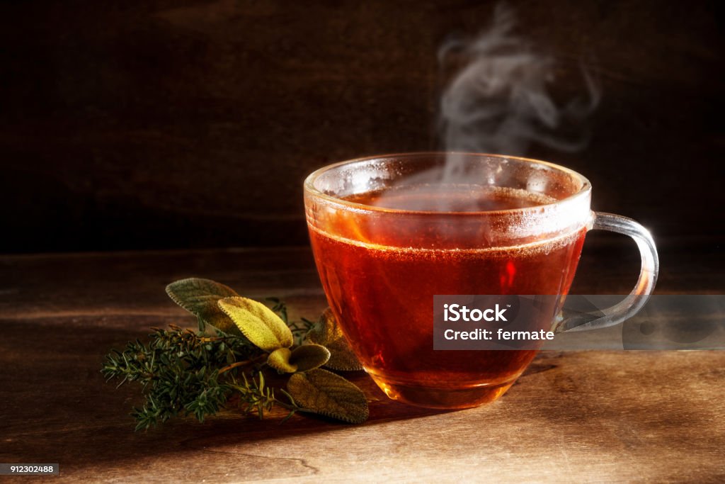 tea freshly brewed in a glass cup and some herbs on a dark rustic wooden background, healthy hot drink against cold and flu, copy space tea freshly brewed in a glass cup and some herbs on a dark rustic wooden background, healthy hot drink against cold and flu, copy space, selected focus Tea - Hot Drink Stock Photo