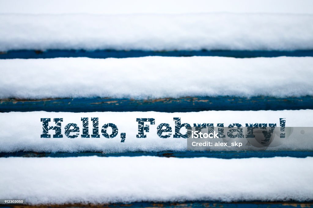 Text Hello February on old wood texture with snow Text Hello February on old wood texture with snow. Backgrounds Stock Photo