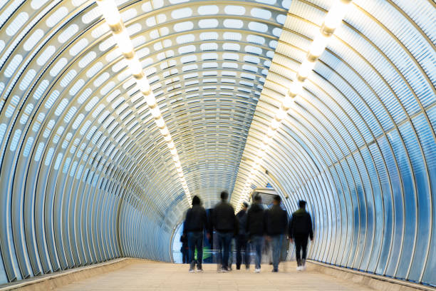 Commuters walking down modern blue tunnel in London, UK