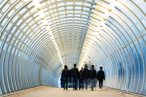 Commuters walking down modern blue tunnel in London, UK