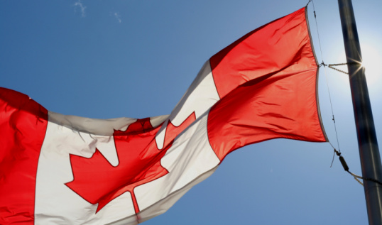 Canada national flag is waving in wind. Bottom view to flag of Canada on flagpole is flapping in wind. Stunning view of Canadian flag with Maple Leaf on it fluttering at sunny day. Proud of Canada