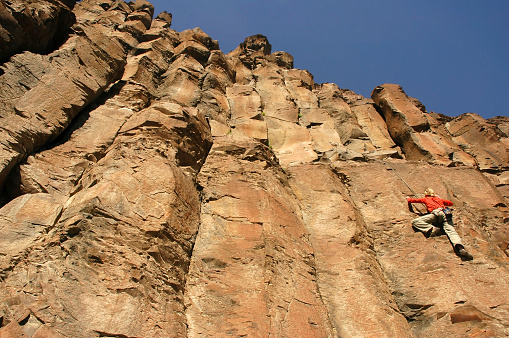 A male climber climbs a mountain using a special rope and climbing equipment