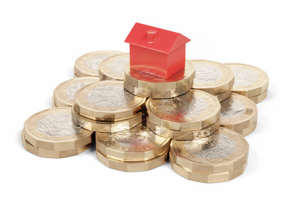 빨간색 장난감 집 새로운 영국 파운드 동전의 스택에 앉아. 흰색 배경입니다. 부동산 투자 개념입니다. - british currency coin british coin heap 뉴스 사진 이미지