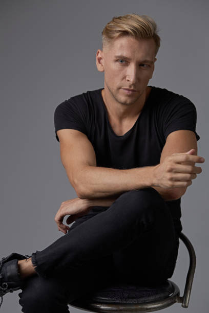 istock Portrait young stylish man model sitting leg over leg thoughtful 912319048