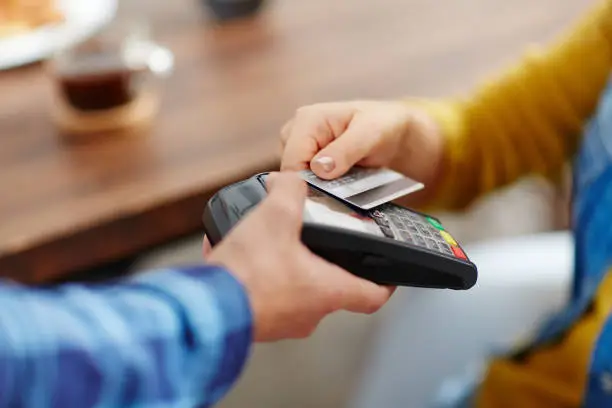 Close-up of unrecognizable customer choosing contactless payment using credit card while waitress accepting payment over nfc technology