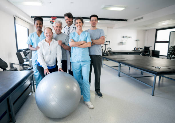 Diverse team of healthcare professionals and patients at a physical rehabilitation clinic Diverse team of healthcare professionals and patients at a physical rehabilitation clinic all looking at camera smiling with arms crossed physical therapist stock pictures, royalty-free photos & images