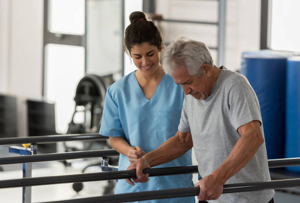istock Physiotherapist helping a senior patient while he walks using his hands to support his weight on the bars 912333808