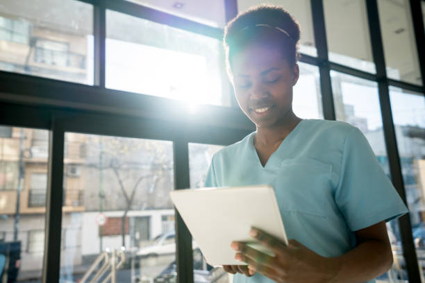 istock Cheerful black nurse taking a break looking at social media on a digital tablet smiling 912333830