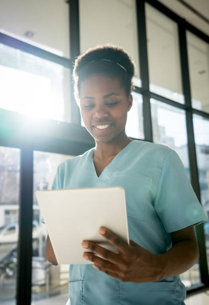 istock Black nurse at the hospital looking at a medical chart on a computer tablet smiling 912333868