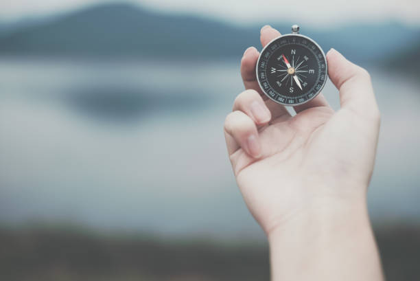 istock hand holding compass for searching direction outdoor. man seeking way with nature background. travel lifestyle, summer vacation concept 912333970