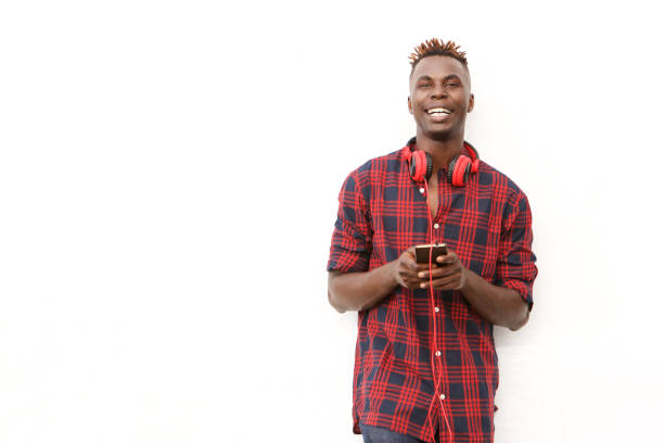 istock Handsome african man with headphones and mobile phone standing by white wall 912334624