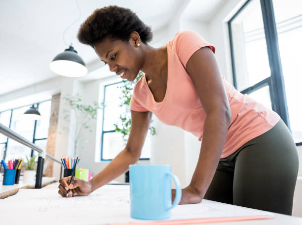 istock Female architect working at the office drawing a blueprint 912334868