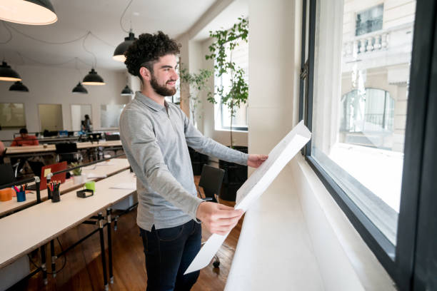 istock Architect holding a blueprint at the office and looking through the window 912335042