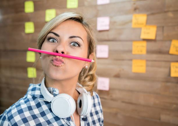 Portrait of a silly woman working at a creative office Portrait of a silly woman working at a creative office making gestures towards the camera office fun business adhesive note stock pictures, royalty-free photos & images