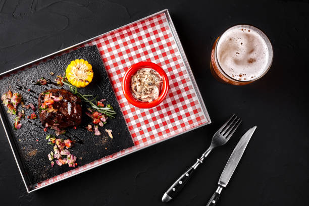 A piece of steak with salad, corn, mushrooms sauce on a blackboard