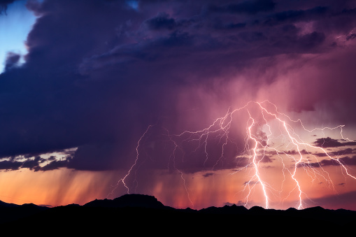 Lightning bolts strike from a monsoon thunderstorm at sunset, in the desert near Congress, Arizona.