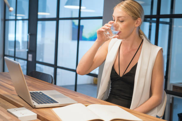 istock Business woman drinking water while working in modern office 912349454