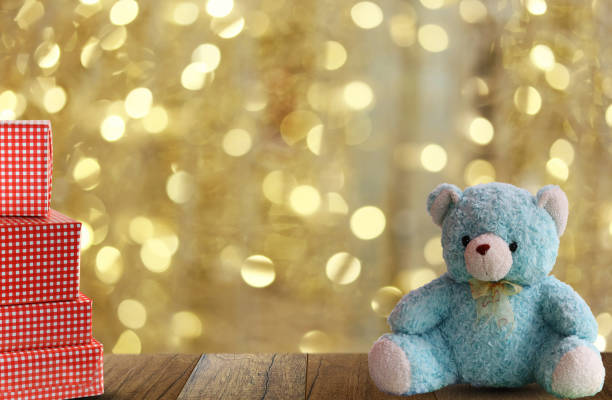 blue bear is placed on a wood plank floor and have red Gift Box on gold bokeh background,copy space to input idea in your work.