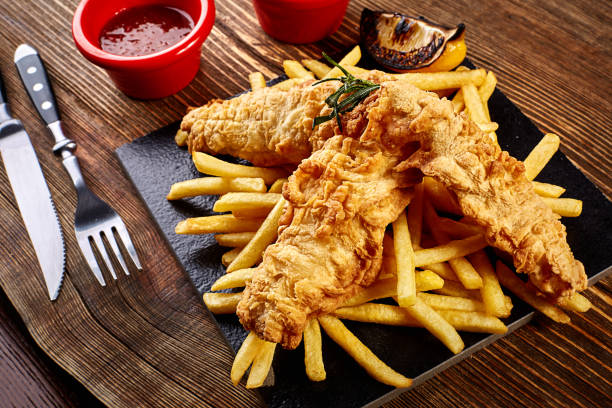 istock Black plate with fish and chips, mayo and ketchup on wooden background 912356436