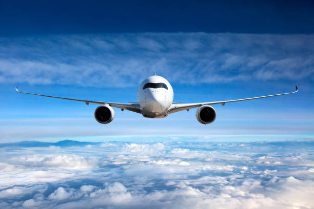 White passenger airplane in the sky. Front view of aircraft in flight. The passenger plane flies high above the clouds. front view stock pictures, royalty-free photos & images