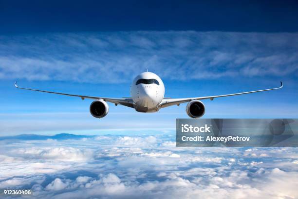 White Passenger Airplane In The Sky Stock Photo - Download Image Now - Airplane, Front View, Aerospace Industry