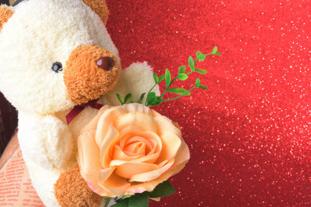 teddy bear with flowers in valentines day on red glitter bokeh lights Blurred abstract background.