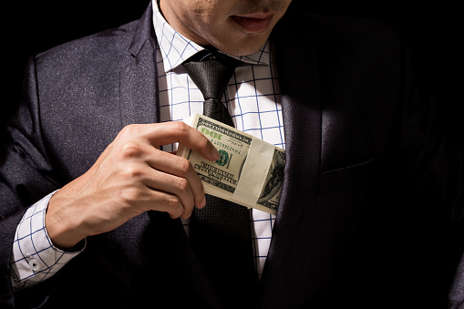 Businessman putting dollar banknotes into pocket