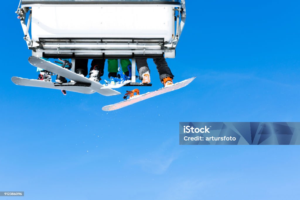 Skiers going up on the chairlift against bright blue sky- ski resort in Italy on sunny winter day Adventure Stock Photo