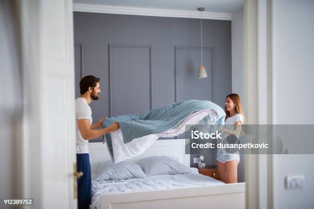 Photo libre de droit de Charmant Beau Couple Amoureux Faire Le Lit Ensemble Et Samuser banque d'images et plus d'images libres de droit de Lit - Ameublement