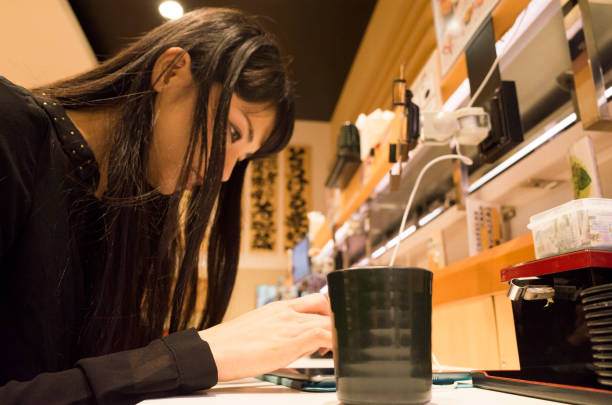 A woman who touches a touch pad with a sushi bar. A woman is manipulating the shop's touchpad at the sushi bar counter seat. kids eating tuna stock pictures, royalty-free photos & images