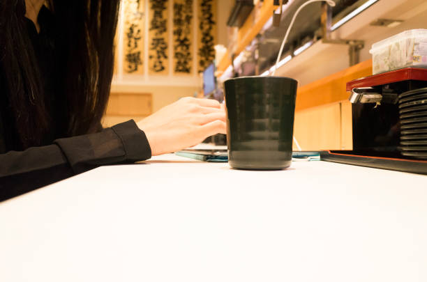 A woman who touches a touch pad with a sushi bar. A woman is manipulating the shop's touchpad at the sushi bar counter seat. kids eating tuna stock pictures, royalty-free photos & images