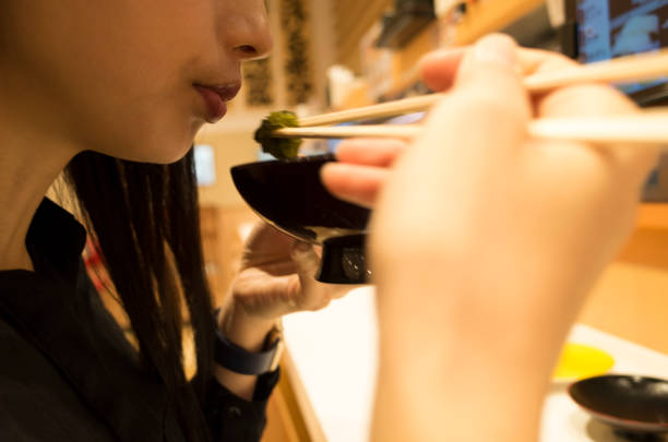 A woman who eats soup in a sushi bar. A person trying to drink soup that entered the bowl at a sushi bar. kids eating tuna stock pictures, royalty-free photos & images
