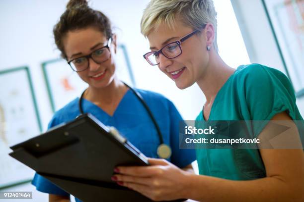 Close Up View Of Two Professional Nurses With Eyeglasses Checking The Patient Papers In A Doctors Office Stock Photo - Download Image Now