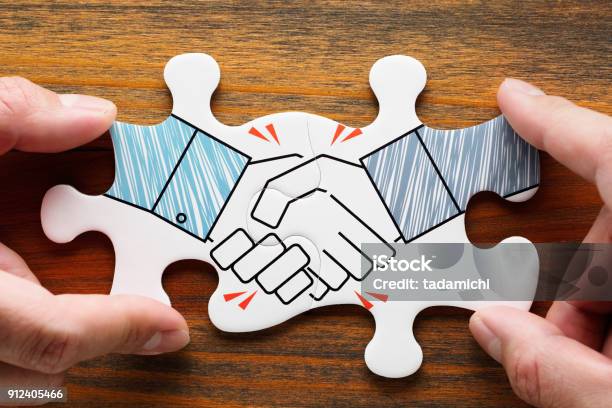 Putting Together Handshake Jigsaw Puzzle Pieces On Wood Desk Stock Photo - Download Image Now