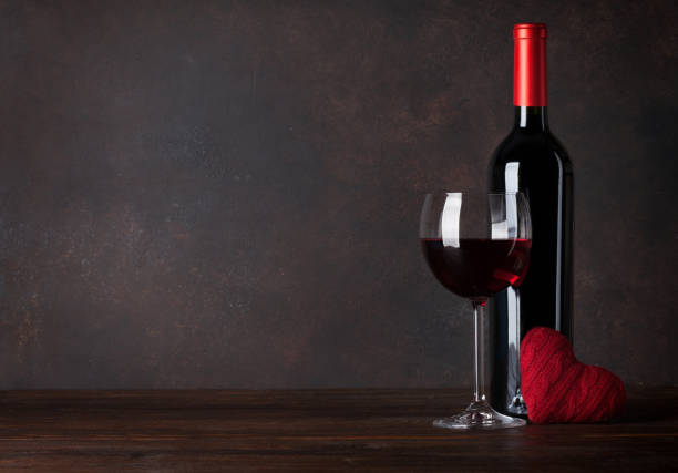 Valentines day greeting card with wine bottle and heart toy on wooden table. With chalkboard for your greetings