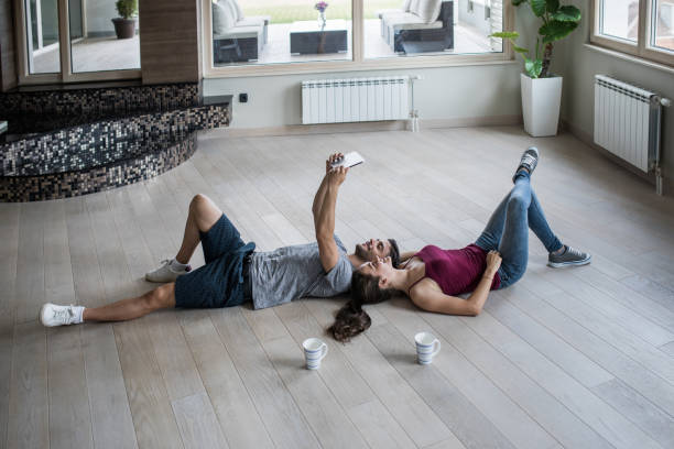 istock Young couple taking a selfie with touchpad while resting on a floor at empty apartment. 912409108