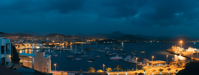 Mindelo in twilight. Port town with many boats in the bay on the Cape Verde in the northern part of the island Sao Vicente. Long exposure panoramic shot.