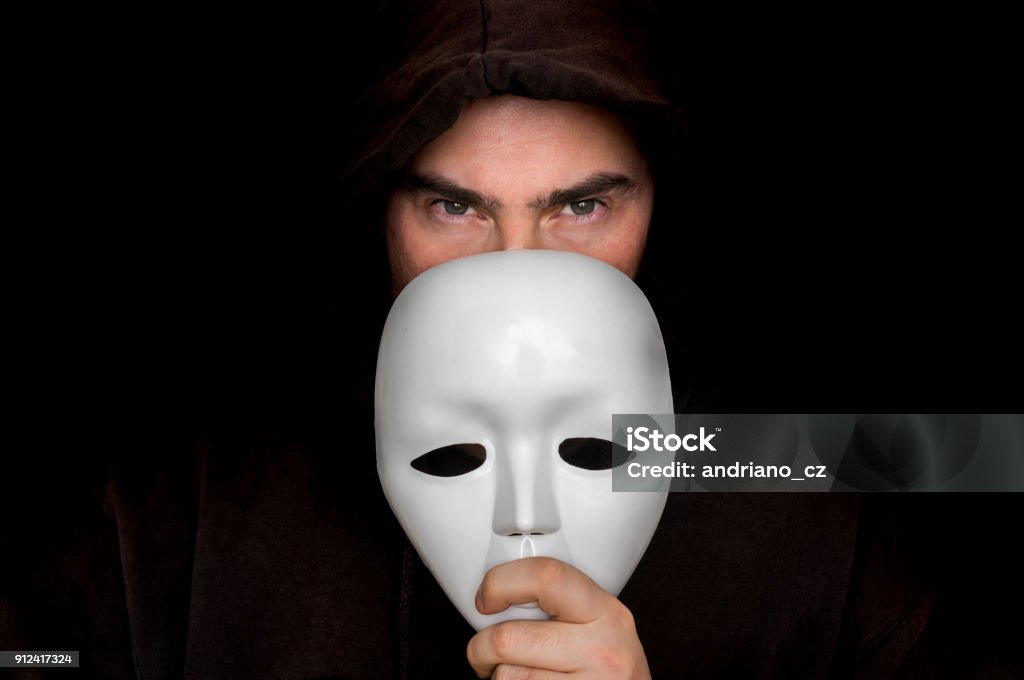 Mysterious man in black hiding his face behind white mask Mysterious man in black hiding his face behind white mask - anonymous concept Scuba Mask Stock Photo