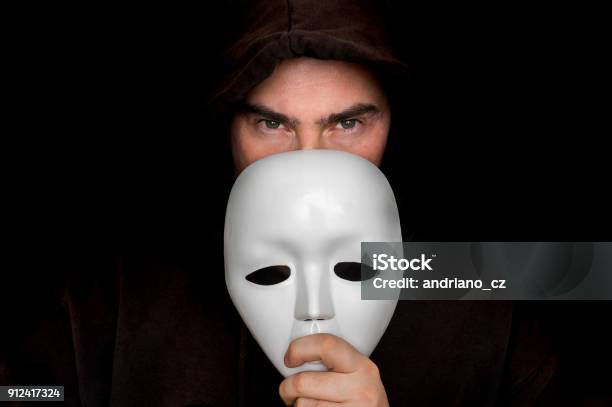 Mysterious Man In Black Hiding His Face Behind White Mask Stock Photo - Download Image Now